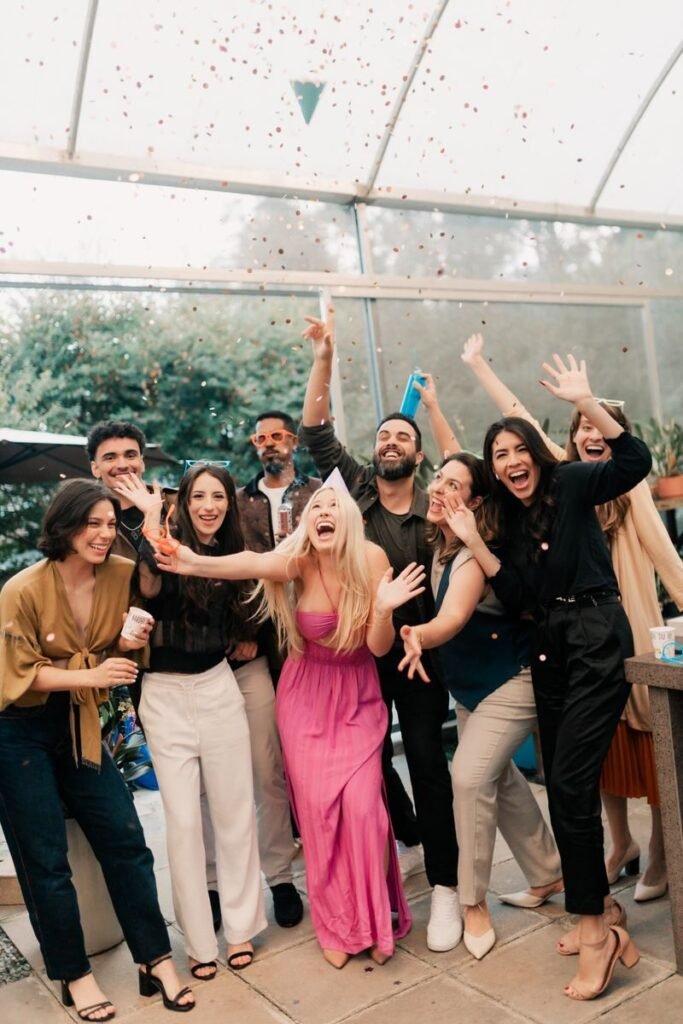 A joyful group of friends celebrating indoors with laughter and confetti.