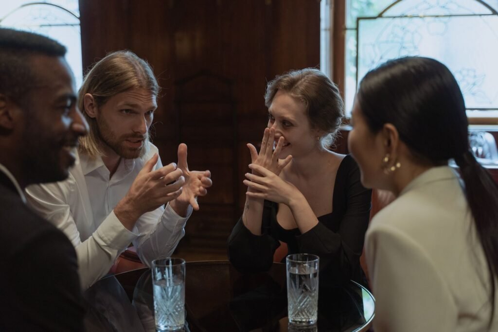 A group of friends talking and laughing around a table in a cozy indoor setting.